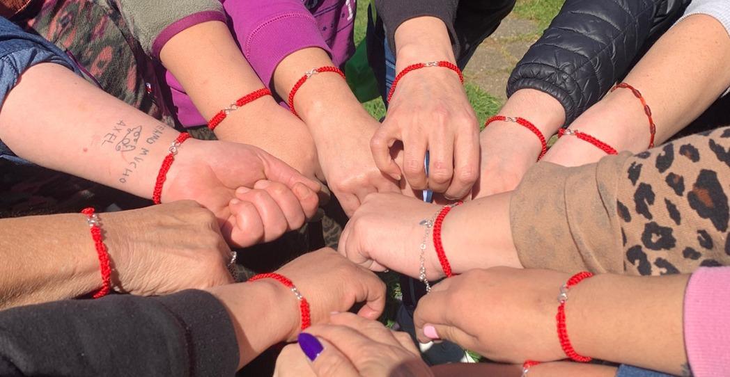 Manos unidas con pulseras rojas